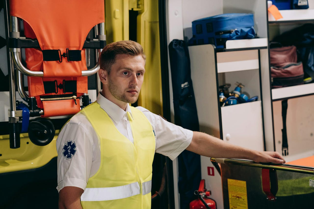 Male paramedic in a reflective vest inside ambulance, ready for emergency response.