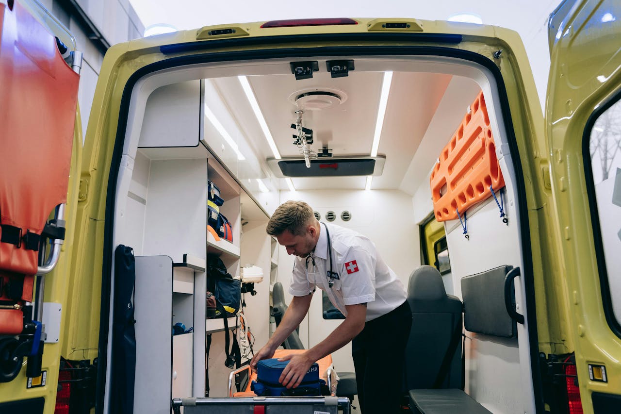 A paramedic arranges medical supplies in an ambulance, showcasing emergency readiness.