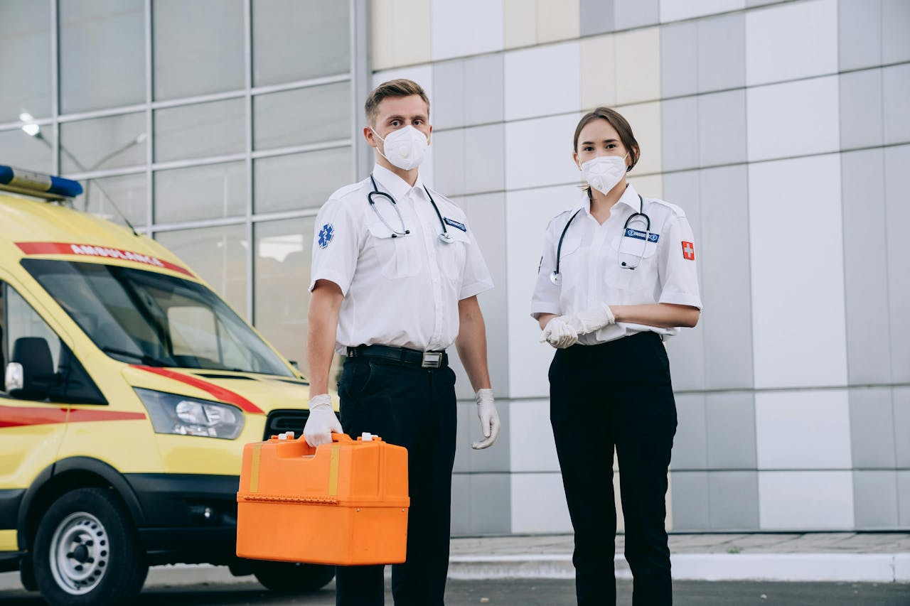 Paramedics standing with medical equipment in front of an ambulance, showcasing emergency healthcare services.